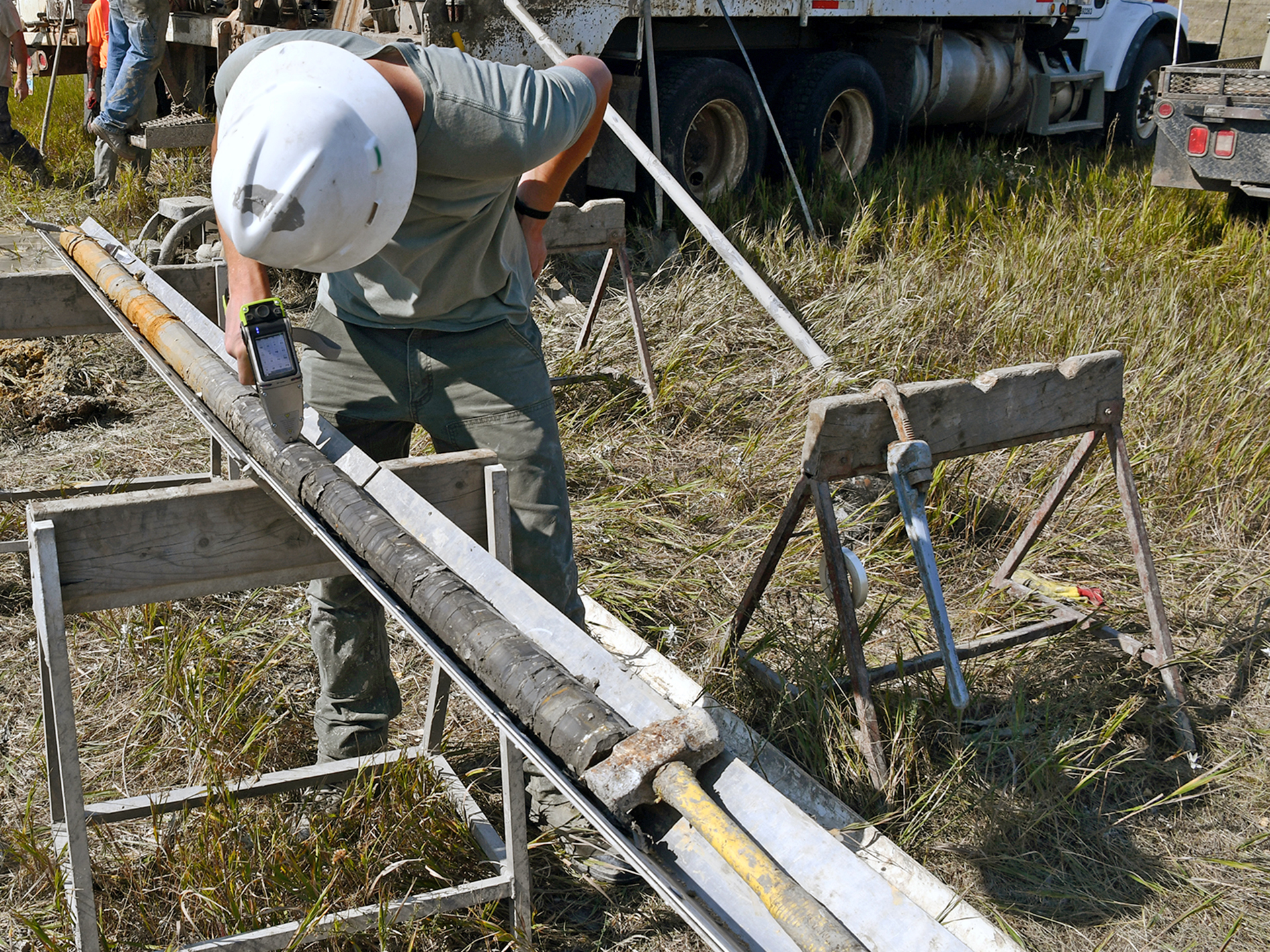 Geologist testing a core sample with a portable xray in the field.