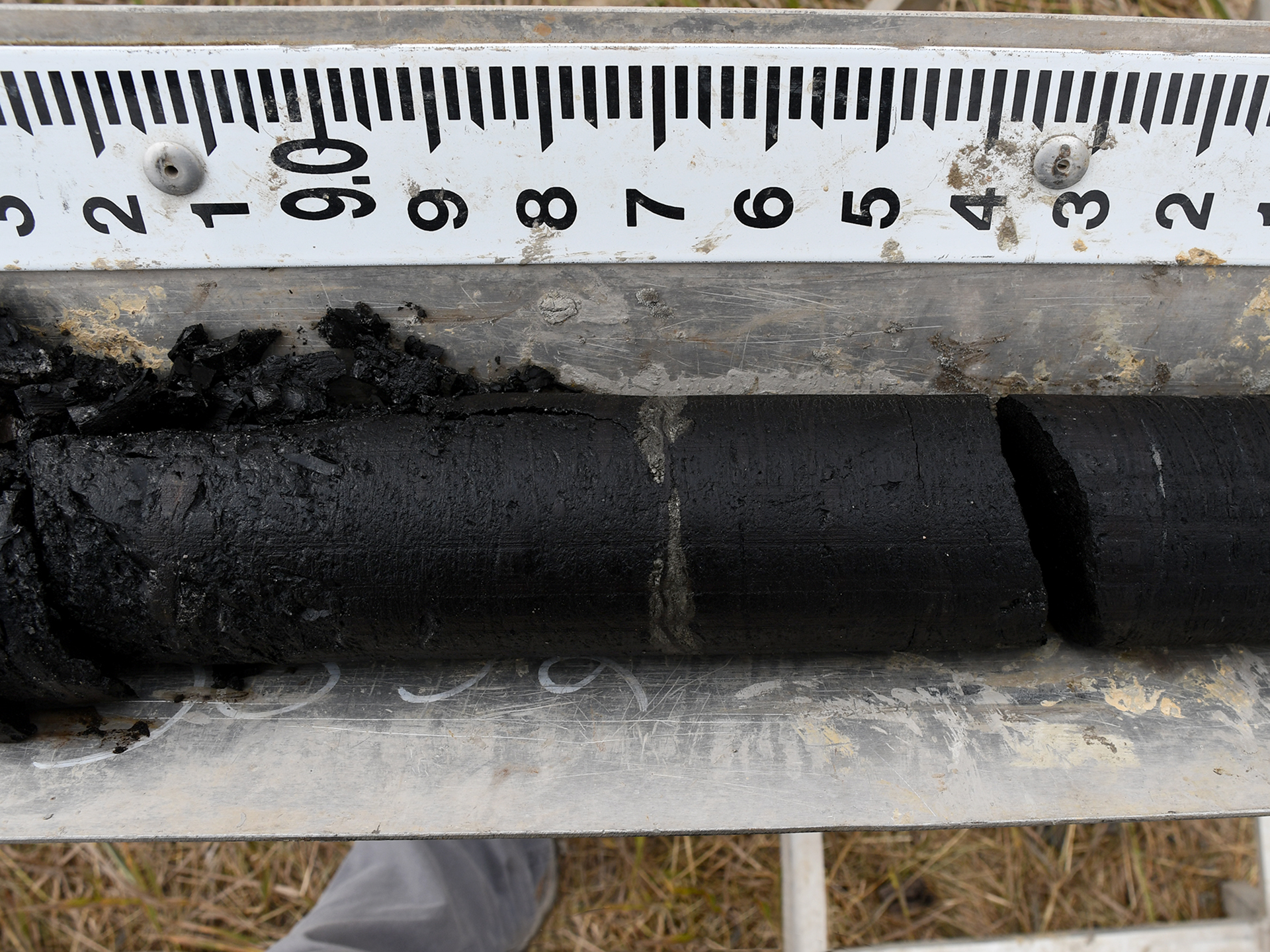 Photograph of a solid black core next to a ruler.