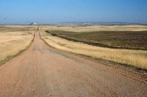 A clinker-covered road leading east to Lone Butte in McKenzie County. The Killdeer Mountains are visible on the horizon. Photo by E. Murphy, NDGS). 